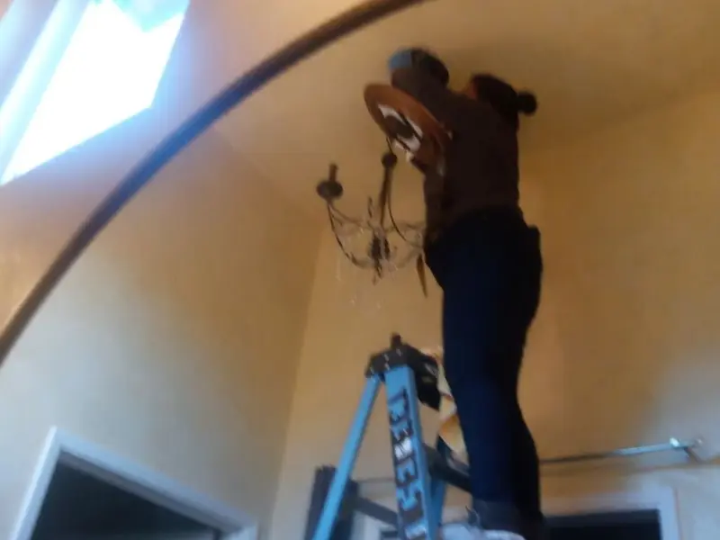 Electrician installing a chandelier in a Crosby residence